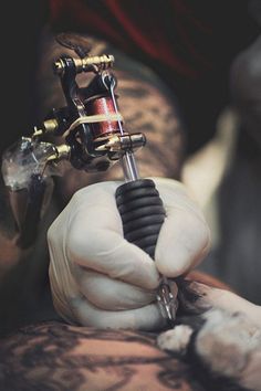 a tattoo artist is working on his arm with a needle and inking pen in it