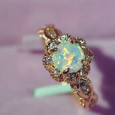 an opal and diamond ring sits on a purple surface