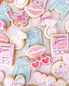 cookies decorated with different designs and colors on a white tablecloth that says, love is in the air