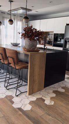 a kitchen with wooden flooring and white cabinetry next to a large center island