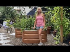 a woman standing next to two large planters