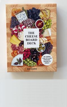 the cheese board book is displayed on a white surface with an assortment of different types of cheeses