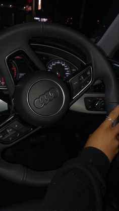 the steering wheel and dashboard of an audi car at night with lights on in the background