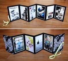 an open photo album with pictures inside on a wooden table next to a yellow ribbon