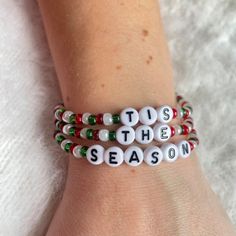 two bracelets with words that say tis the season on them, sitting on a person's arm