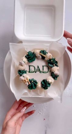 someone is holding a white box with green and white flowers on it that says dad