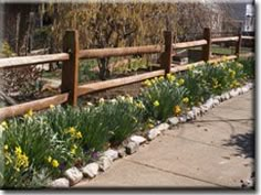 a wooden fence with flowers growing along it