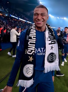 a man wearing a scarf standing on top of a soccer field with fans in the background