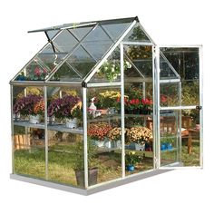 a small greenhouse with several plants growing in the ground and flowers on the shelves inside