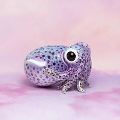 a glass figurine sitting on top of a pink surface with polka dot designs