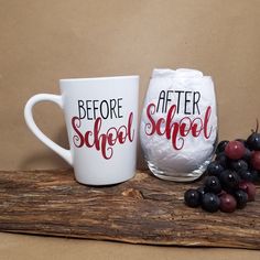 two coffee mugs sitting next to each other on a piece of wood with grapes