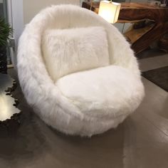 a large white chair sitting on top of a metal table next to a potted plant