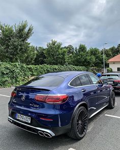 the rear end of a blue mercedes suv parked in a parking lot with other cars