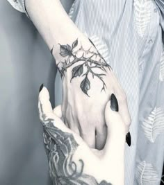 a woman's hand with tattoos on it holding onto her wrist and the other arm