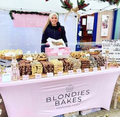 a woman standing behind a table full of baked goods