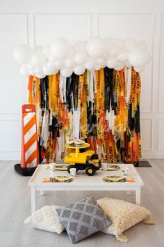 a construction themed birthday party with balloons and streamers on the wall, including an excavator truck