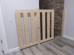 an open wooden gate in the corner of a room with wood flooring and white walls