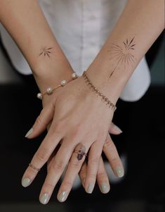 a woman's hands with two tattoos on her wrist and one has a starburst tattoo