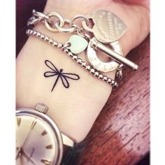 a woman's wrist with a dragonfly tattoo on it and a watch in the background