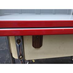 an old red and white table with metal handles