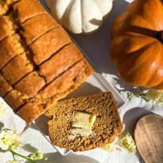 a loaf of bread with butter on it next to some flowers and pumpkins in the background