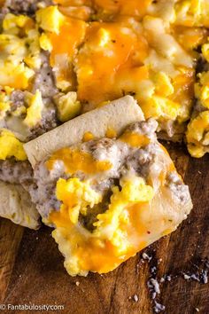 breakfast burritos with eggs and cheese are on a cutting board, ready to be eaten