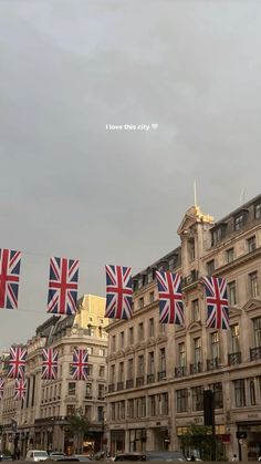 several british flags are flying in the air over a city street with cars and buildings