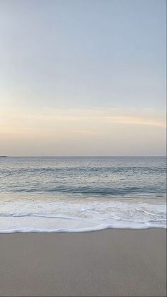 an empty beach with the ocean in the background