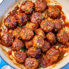 meatballs covered in marinara sauce and parsley in a skillet on top of a blue towel