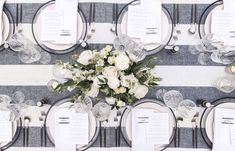 the table is set with white flowers and place settings