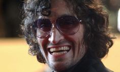 a close up of a person wearing sunglasses and smiling at the camera with his mouth open