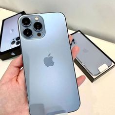 an iphone 11 pro is being held up by someone's hand with two other phones in the background