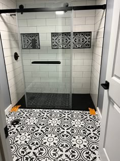 a bathroom with black and white tiles on the floor, shower stall door and toilet