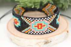 Introducing our southwestern cross cuff bracelet- perfect for adding a touch of boho chic to any outfit! This bracelet is handmade with black leather trim and colorful seed beads, and features an adjustable closure for a perfect fit. It is beaded on strong beading thread & flexible natural leather for comfortable stylish look. It can be worn alone or stacked with other pieces. 7/8 of an inch wide. This bracelet will fit a 6-8 inch wrist. When you purchase this bracelet, I make it to order, just Adjustable Black Cuff Bracelet With Colorful Beads, Handmade Southwestern Black Beaded Bracelets, Handmade Black Southwestern Beaded Bracelets, Southwestern Black Beaded Bracelet With Colorful Beads, Black Beaded Southwestern Bracelets, Southwestern Black Beaded Bracelets, Southwestern Style Black Beaded Bracelet With Colorful Beads, Southwestern Black Bracelets For Festival, Southwestern Style Black Beaded Bracelets