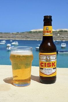 a beer bottle and glass sitting on a table next to the ocean