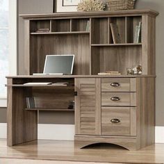 a computer desk with drawers and a laptop on it in front of a bookcase