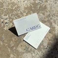 two business cards sitting on top of a stone floor with the word cardo printed on them