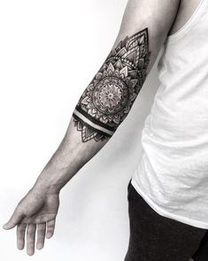 a man's arm with a black and white tattoo design on the left forearm