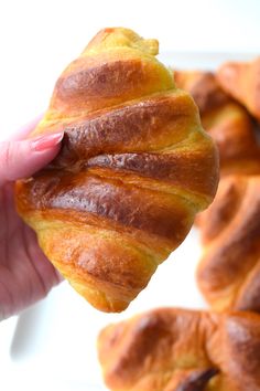 a person holding up a croissant in their hand