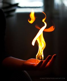 a person holding out their hand with fire in the middle and flames coming out of it