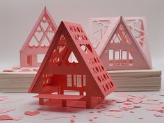 three pink paper houses with hearts on them and confetti scattered all over the floor