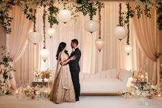 a man and woman standing in front of a white couch with floral decorations on it