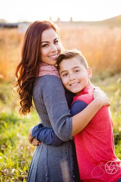 a woman hugging a boy in a field