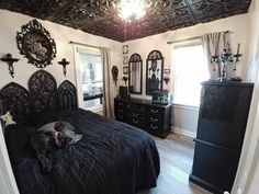 a dog laying on top of a black bed in a bedroom next to a dresser