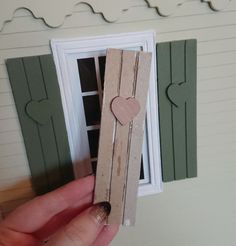 someone is holding up a piece of cardboard with a heart on it in front of a window