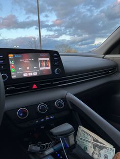 the dashboard of a car with an electronic device on it's dash board and money in front of it