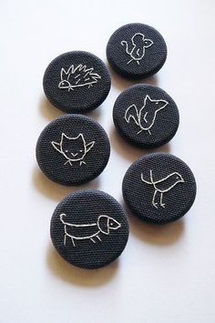 four black buttons with white drawings on them