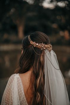 a woman wearing a veil with a head piece on her head and pearls in the hair