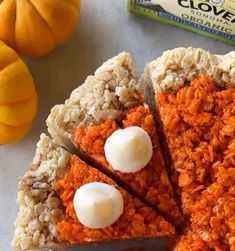 an orange cake with white frosting sitting on top of a table next to pumpkins