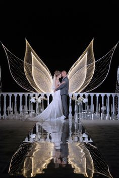 a bride and groom standing in front of fairy wings